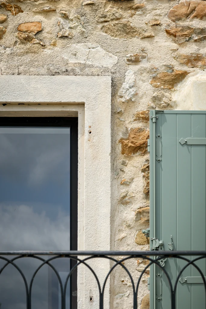 Rénovation complète d’une maison de famille – Drôme
Nichée au cœur des paysages de la Drôme, cette maison a fait l’objet d’une rénovation intégrale. Le projet a consisté à redonner vie à une bâtisse aux volumes autrefois fermés et cloisonnés, pour en révéler tout le potentiel architectural et spatial.
L’intervention a porté sur l’ensemble de l’enveloppe : les façades ont été restaurées, les ouvertures repensées et créées pour offrir de nouveaux cadrages sur le paysage, mettant en valeur la pierre existante et la richesse du contexte environnant.
À l’intérieur, les espaces ont été entièrement réorganisés. Le plan initial, fragmenté et contraint, a laissé place à des enchaînements fluides, où les pièces dialoguent entre elles et s’ouvrent généreusement sur l’extérieur. Chaque ouverture devient un tableau vivant, cadrant une portion de nature : champs de blé, forêt, lumière changeante.
Le cœur de la maison se structure autour de volumes entremêlés. Une cheminée centrale, élément à la fois architectural et domestique, relie les grands volumes de la cuisine en double hauteur et le salon, plus intime et chaleureux. Dans une autre aile, à l’étage, une seconde cuisine a été aménagée. Elle prolonge l’esprit du projet : fonctionnalité discrète, ouverture maîtrisée, cadrages sensibles sur le paysage.
Les ambiances varient selon les espaces : une chambre se déploie autour d’un vide intérieur, jouant avec les hauteurs et les couleurs ; le salon TV, équipé d’une bibliothèque et de rangements intégrés, offre un lieu de retrait, propice au calme tout en restant connecté à l’extérieur.
Le choix des matériaux renforce l’identité sobre et chaleureuse du lieu : pierre naturelle, travertin, parquet en chêne et surfaces en solid surface s’équilibrent pour créer une atmosphère douce, intemporelle et raffinée.
Les ouvertures ont été dessinées pour favoriser la lumière naturelle et créer des liens visuels avec le paysage, tout en accompagnant les usages quotidiens. À l’extérieur, une piscine s’insère discrètement dans le jardin paysager, entourée de terrasses orientées pour profiter du soleil tout au long de la journée. La maison se fond progressivement dans son environnement, entre les cultures et les bois, dans un dialogue apaisé avec le site.
Enfin, les espaces de nuit, regroupés dans une aile plus en retrait, assurent calme et sérénité. Ils sont complétés par une salle de sport et un second salon dédié aux plus jeunes, pour que chacun puisse vivre la maison à son rythme, en toute liberté.