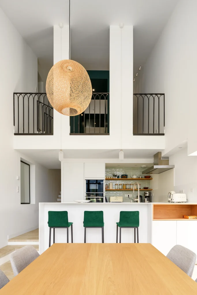 Rénovation complète d’une maison de famille – Drôme
Nichée au cœur des paysages de la Drôme, cette maison a fait l’objet d’une rénovation intégrale. Le projet a consisté à redonner vie à une bâtisse aux volumes autrefois fermés et cloisonnés, pour en révéler tout le potentiel architectural et spatial.
L’intervention a porté sur l’ensemble de l’enveloppe : les façades ont été restaurées, les ouvertures repensées et créées pour offrir de nouveaux cadrages sur le paysage, mettant en valeur la pierre existante et la richesse du contexte environnant.
À l’intérieur, les espaces ont été entièrement réorganisés. Le plan initial, fragmenté et contraint, a laissé place à des enchaînements fluides, où les pièces dialoguent entre elles et s’ouvrent généreusement sur l’extérieur. Chaque ouverture devient un tableau vivant, cadrant une portion de nature : champs de blé, forêt, lumière changeante.
Le cœur de la maison se structure autour de volumes entremêlés. Une cheminée centrale, élément à la fois architectural et domestique, relie les grands volumes de la cuisine en double hauteur et le salon, plus intime et chaleureux. Dans une autre aile, à l’étage, une seconde cuisine a été aménagée. Elle prolonge l’esprit du projet : fonctionnalité discrète, ouverture maîtrisée, cadrages sensibles sur le paysage.
Les ambiances varient selon les espaces : une chambre se déploie autour d’un vide intérieur, jouant avec les hauteurs et les couleurs ; le salon TV, équipé d’une bibliothèque et de rangements intégrés, offre un lieu de retrait, propice au calme tout en restant connecté à l’extérieur.
Le choix des matériaux renforce l’identité sobre et chaleureuse du lieu : pierre naturelle, travertin, parquet en chêne et surfaces en solid surface s’équilibrent pour créer une atmosphère douce, intemporelle et raffinée.
Les ouvertures ont été dessinées pour favoriser la lumière naturelle et créer des liens visuels avec le paysage, tout en accompagnant les usages quotidiens. À l’extérieur, une piscine s’insère discrètement dans le jardin paysager, entourée de terrasses orientées pour profiter du soleil tout au long de la journée. La maison se fond progressivement dans son environnement, entre les cultures et les bois, dans un dialogue apaisé avec le site.
Enfin, les espaces de nuit, regroupés dans une aile plus en retrait, assurent calme et sérénité. Ils sont complétés par une salle de sport et un second salon dédié aux plus jeunes, pour que chacun puisse vivre la maison à son rythme, en toute liberté.