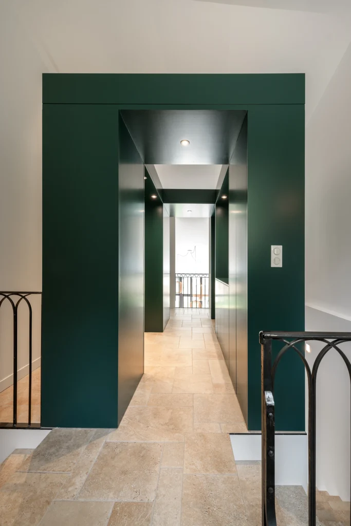 Rénovation complète d’une maison de famille – Drôme
Nichée au cœur des paysages de la Drôme, cette maison a fait l’objet d’une rénovation intégrale. Le projet a consisté à redonner vie à une bâtisse aux volumes autrefois fermés et cloisonnés, pour en révéler tout le potentiel architectural et spatial.
L’intervention a porté sur l’ensemble de l’enveloppe : les façades ont été restaurées, les ouvertures repensées et créées pour offrir de nouveaux cadrages sur le paysage, mettant en valeur la pierre existante et la richesse du contexte environnant.
À l’intérieur, les espaces ont été entièrement réorganisés. Le plan initial, fragmenté et contraint, a laissé place à des enchaînements fluides, où les pièces dialoguent entre elles et s’ouvrent généreusement sur l’extérieur. Chaque ouverture devient un tableau vivant, cadrant une portion de nature : champs de blé, forêt, lumière changeante.
Le cœur de la maison se structure autour de volumes entremêlés. Une cheminée centrale, élément à la fois architectural et domestique, relie les grands volumes de la cuisine en double hauteur et le salon, plus intime et chaleureux. Dans une autre aile, à l’étage, une seconde cuisine a été aménagée. Elle prolonge l’esprit du projet : fonctionnalité discrète, ouverture maîtrisée, cadrages sensibles sur le paysage.
Les ambiances varient selon les espaces : une chambre se déploie autour d’un vide intérieur, jouant avec les hauteurs et les couleurs ; le salon TV, équipé d’une bibliothèque et de rangements intégrés, offre un lieu de retrait, propice au calme tout en restant connecté à l’extérieur.
Le choix des matériaux renforce l’identité sobre et chaleureuse du lieu : pierre naturelle, travertin, parquet en chêne et surfaces en solid surface s’équilibrent pour créer une atmosphère douce, intemporelle et raffinée.
Les ouvertures ont été dessinées pour favoriser la lumière naturelle et créer des liens visuels avec le paysage, tout en accompagnant les usages quotidiens. À l’extérieur, une piscine s’insère discrètement dans le jardin paysager, entourée de terrasses orientées pour profiter du soleil tout au long de la journée. La maison se fond progressivement dans son environnement, entre les cultures et les bois, dans un dialogue apaisé avec le site.
Enfin, les espaces de nuit, regroupés dans une aile plus en retrait, assurent calme et sérénité. Ils sont complétés par une salle de sport et un second salon dédié aux plus jeunes, pour que chacun puisse vivre la maison à son rythme, en toute liberté.