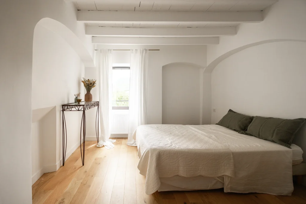 Rénovation complète d’une maison de famille – Drôme
Nichée au cœur des paysages de la Drôme, cette maison a fait l’objet d’une rénovation intégrale. Le projet a consisté à redonner vie à une bâtisse aux volumes autrefois fermés et cloisonnés, pour en révéler tout le potentiel architectural et spatial.
L’intervention a porté sur l’ensemble de l’enveloppe : les façades ont été restaurées, les ouvertures repensées et créées pour offrir de nouveaux cadrages sur le paysage, mettant en valeur la pierre existante et la richesse du contexte environnant.
À l’intérieur, les espaces ont été entièrement réorganisés. Le plan initial, fragmenté et contraint, a laissé place à des enchaînements fluides, où les pièces dialoguent entre elles et s’ouvrent généreusement sur l’extérieur. Chaque ouverture devient un tableau vivant, cadrant une portion de nature : champs de blé, forêt, lumière changeante.
Le cœur de la maison se structure autour de volumes entremêlés. Une cheminée centrale, élément à la fois architectural et domestique, relie les grands volumes de la cuisine en double hauteur et le salon, plus intime et chaleureux. Dans une autre aile, à l’étage, une seconde cuisine a été aménagée. Elle prolonge l’esprit du projet : fonctionnalité discrète, ouverture maîtrisée, cadrages sensibles sur le paysage.
Les ambiances varient selon les espaces : une chambre se déploie autour d’un vide intérieur, jouant avec les hauteurs et les couleurs ; le salon TV, équipé d’une bibliothèque et de rangements intégrés, offre un lieu de retrait, propice au calme tout en restant connecté à l’extérieur.
Le choix des matériaux renforce l’identité sobre et chaleureuse du lieu : pierre naturelle, travertin, parquet en chêne et surfaces en solid surface s’équilibrent pour créer une atmosphère douce, intemporelle et raffinée.
Les ouvertures ont été dessinées pour favoriser la lumière naturelle et créer des liens visuels avec le paysage, tout en accompagnant les usages quotidiens. À l’extérieur, une piscine s’insère discrètement dans le jardin paysager, entourée de terrasses orientées pour profiter du soleil tout au long de la journée. La maison se fond progressivement dans son environnement, entre les cultures et les bois, dans un dialogue apaisé avec le site.
Enfin, les espaces de nuit, regroupés dans une aile plus en retrait, assurent calme et sérénité. Ils sont complétés par une salle de sport et un second salon dédié aux plus jeunes, pour que chacun puisse vivre la maison à son rythme, en toute liberté.