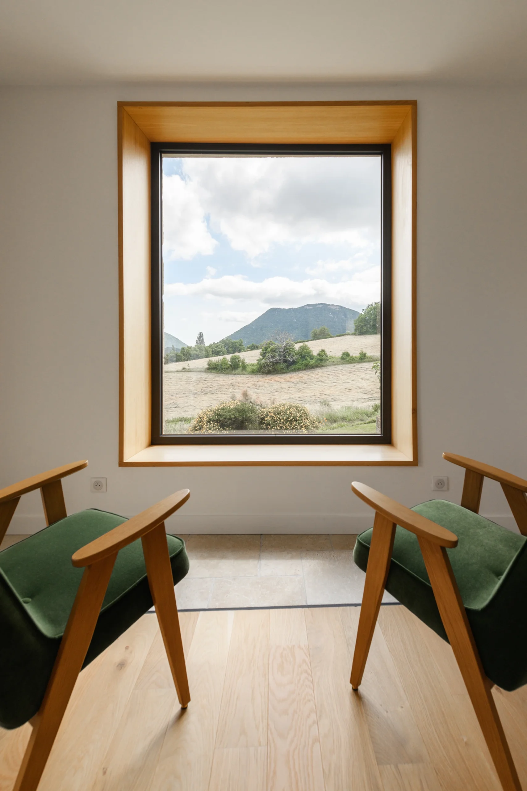 Rénovation d’une maison en Drôme ouverte sur le paysage, avec façades en pierre restaurées, grandes baies vitrées, espaces intérieurs décloisonnés et aménagements extérieurs paysagers avec piscine.