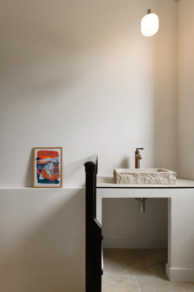 Rénovation complète d’une maison de famille – Drôme
Nichée au cœur des paysages de la Drôme, cette maison a fait l’objet d’une rénovation intégrale. Le projet a consisté à redonner vie à une bâtisse aux volumes autrefois fermés et cloisonnés, pour en révéler tout le potentiel architectural et spatial.
L’intervention a porté sur l’ensemble de l’enveloppe : les façades ont été restaurées, les ouvertures repensées et créées pour offrir de nouveaux cadrages sur le paysage, mettant en valeur la pierre existante et la richesse du contexte environnant.
À l’intérieur, les espaces ont été entièrement réorganisés. Le plan initial, fragmenté et contraint, a laissé place à des enchaînements fluides, où les pièces dialoguent entre elles et s’ouvrent généreusement sur l’extérieur. Chaque ouverture devient un tableau vivant, cadrant une portion de nature : champs de blé, forêt, lumière changeante.
Le cœur de la maison se structure autour de volumes entremêlés. Une cheminée centrale, élément à la fois architectural et domestique, relie les grands volumes de la cuisine en double hauteur et le salon, plus intime et chaleureux. Dans une autre aile, à l’étage, une seconde cuisine a été aménagée. Elle prolonge l’esprit du projet : fonctionnalité discrète, ouverture maîtrisée, cadrages sensibles sur le paysage.
Les ambiances varient selon les espaces : une chambre se déploie autour d’un vide intérieur, jouant avec les hauteurs et les couleurs ; le salon TV, équipé d’une bibliothèque et de rangements intégrés, offre un lieu de retrait, propice au calme tout en restant connecté à l’extérieur.
Le choix des matériaux renforce l’identité sobre et chaleureuse du lieu : pierre naturelle, travertin, parquet en chêne et surfaces en solid surface s’équilibrent pour créer une atmosphère douce, intemporelle et raffinée.
Les ouvertures ont été dessinées pour favoriser la lumière naturelle et créer des liens visuels avec le paysage, tout en accompagnant les usages quotidiens. À l’extérieur, une piscine s’insère discrètement dans le jardin paysager, entourée de terrasses orientées pour profiter du soleil tout au long de la journée. La maison se fond progressivement dans son environnement, entre les cultures et les bois, dans un dialogue apaisé avec le site.
Enfin, les espaces de nuit, regroupés dans une aile plus en retrait, assurent calme et sérénité. Ils sont complétés par une salle de sport et un second salon dédié aux plus jeunes, pour que chacun puisse vivre la maison à son rythme, en toute liberté.