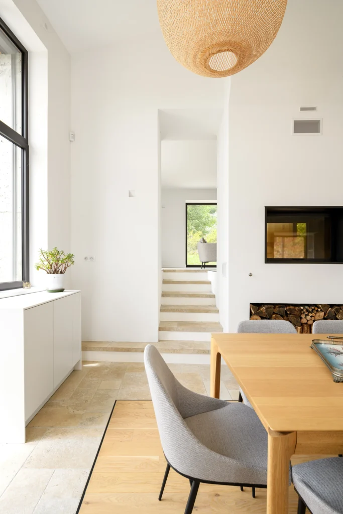 Rénovation complète d’une maison de famille – Drôme
Nichée au cœur des paysages de la Drôme, cette maison a fait l’objet d’une rénovation intégrale. Le projet a consisté à redonner vie à une bâtisse aux volumes autrefois fermés et cloisonnés, pour en révéler tout le potentiel architectural et spatial.
L’intervention a porté sur l’ensemble de l’enveloppe : les façades ont été restaurées, les ouvertures repensées et créées pour offrir de nouveaux cadrages sur le paysage, mettant en valeur la pierre existante et la richesse du contexte environnant.
À l’intérieur, les espaces ont été entièrement réorganisés. Le plan initial, fragmenté et contraint, a laissé place à des enchaînements fluides, où les pièces dialoguent entre elles et s’ouvrent généreusement sur l’extérieur. Chaque ouverture devient un tableau vivant, cadrant une portion de nature : champs de blé, forêt, lumière changeante.
Le cœur de la maison se structure autour de volumes entremêlés. Une cheminée centrale, élément à la fois architectural et domestique, relie les grands volumes de la cuisine en double hauteur et le salon, plus intime et chaleureux. Dans une autre aile, à l’étage, une seconde cuisine a été aménagée. Elle prolonge l’esprit du projet : fonctionnalité discrète, ouverture maîtrisée, cadrages sensibles sur le paysage.
Les ambiances varient selon les espaces : une chambre se déploie autour d’un vide intérieur, jouant avec les hauteurs et les couleurs ; le salon TV, équipé d’une bibliothèque et de rangements intégrés, offre un lieu de retrait, propice au calme tout en restant connecté à l’extérieur.
Le choix des matériaux renforce l’identité sobre et chaleureuse du lieu : pierre naturelle, travertin, parquet en chêne et surfaces en solid surface s’équilibrent pour créer une atmosphère douce, intemporelle et raffinée.
Les ouvertures ont été dessinées pour favoriser la lumière naturelle et créer des liens visuels avec le paysage, tout en accompagnant les usages quotidiens. À l’extérieur, une piscine s’insère discrètement dans le jardin paysager, entourée de terrasses orientées pour profiter du soleil tout au long de la journée. La maison se fond progressivement dans son environnement, entre les cultures et les bois, dans un dialogue apaisé avec le site.
Enfin, les espaces de nuit, regroupés dans une aile plus en retrait, assurent calme et sérénité. Ils sont complétés par une salle de sport et un second salon dédié aux plus jeunes, pour que chacun puisse vivre la maison à son rythme, en toute liberté.