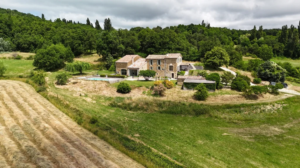 Rénovation complète d’une maison de famille – Drôme
Nichée au cœur des paysages de la Drôme, cette maison a fait l’objet d’une rénovation intégrale. Le projet a consisté à redonner vie à une bâtisse aux volumes autrefois fermés et cloisonnés, pour en révéler tout le potentiel architectural et spatial.
L’intervention a porté sur l’ensemble de l’enveloppe : les façades ont été restaurées, les ouvertures repensées et créées pour offrir de nouveaux cadrages sur le paysage, mettant en valeur la pierre existante et la richesse du contexte environnant.
À l’intérieur, les espaces ont été entièrement réorganisés. Le plan initial, fragmenté et contraint, a laissé place à des enchaînements fluides, où les pièces dialoguent entre elles et s’ouvrent généreusement sur l’extérieur. Chaque ouverture devient un tableau vivant, cadrant une portion de nature : champs de blé, forêt, lumière changeante.
Le cœur de la maison se structure autour de volumes entremêlés. Une cheminée centrale, élément à la fois architectural et domestique, relie les grands volumes de la cuisine en double hauteur et le salon, plus intime et chaleureux. Dans une autre aile, à l’étage, une seconde cuisine a été aménagée. Elle prolonge l’esprit du projet : fonctionnalité discrète, ouverture maîtrisée, cadrages sensibles sur le paysage.
Les ambiances varient selon les espaces : une chambre se déploie autour d’un vide intérieur, jouant avec les hauteurs et les couleurs ; le salon TV, équipé d’une bibliothèque et de rangements intégrés, offre un lieu de retrait, propice au calme tout en restant connecté à l’extérieur.
Le choix des matériaux renforce l’identité sobre et chaleureuse du lieu : pierre naturelle, travertin, parquet en chêne et surfaces en solid surface s’équilibrent pour créer une atmosphère douce, intemporelle et raffinée.
Les ouvertures ont été dessinées pour favoriser la lumière naturelle et créer des liens visuels avec le paysage, tout en accompagnant les usages quotidiens. À l’extérieur, une piscine s’insère discrètement dans le jardin paysager, entourée de terrasses orientées pour profiter du soleil tout au long de la journée. La maison se fond progressivement dans son environnement, entre les cultures et les bois, dans un dialogue apaisé avec le site.
Enfin, les espaces de nuit, regroupés dans une aile plus en retrait, assurent calme et sérénité. Ils sont complétés par une salle de sport et un second salon dédié aux plus jeunes, pour que chacun puisse vivre la maison à son rythme, en toute liberté.