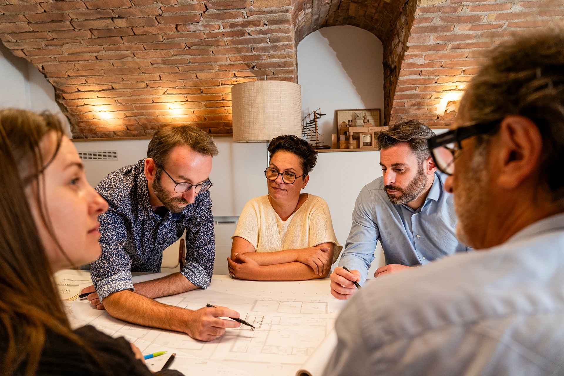 Équipe de l’Atelier TDR Architectes réunie autour de plans lors d’une séance de travail et de conception architecturale.