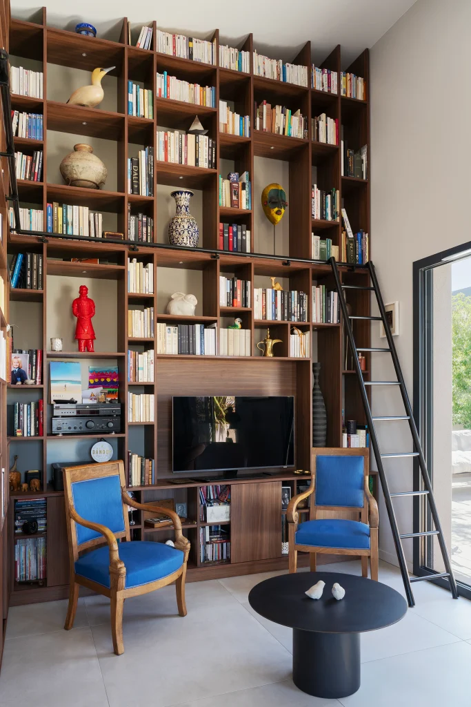 La bibliothèque toute hauteur structure le séjour et personnalise cet intérieur contemporain largement ouvert sur la lumière naturelle.