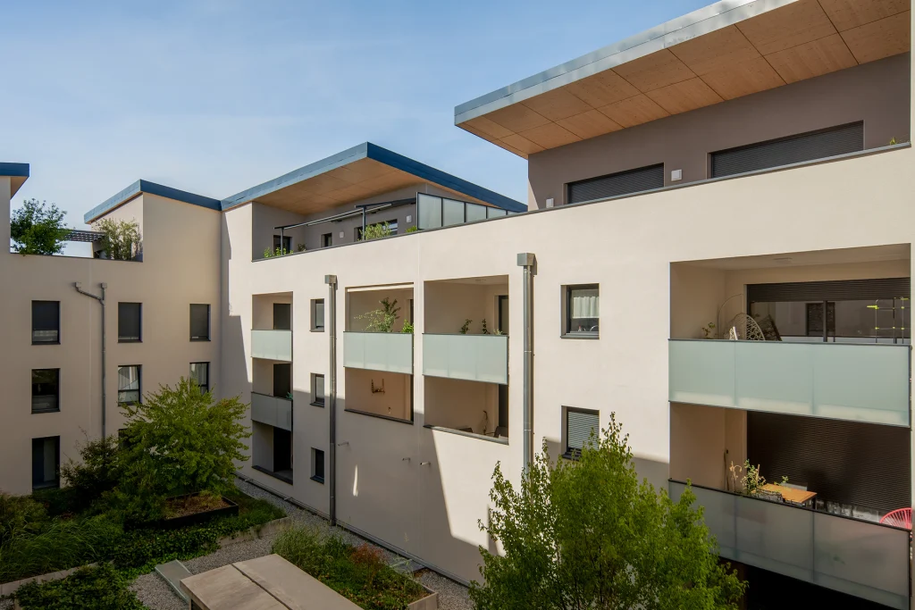 Vue du cœur de résidence où architecture et paysage se rencontrent autour des terrasses, loggias et espaces plantés.