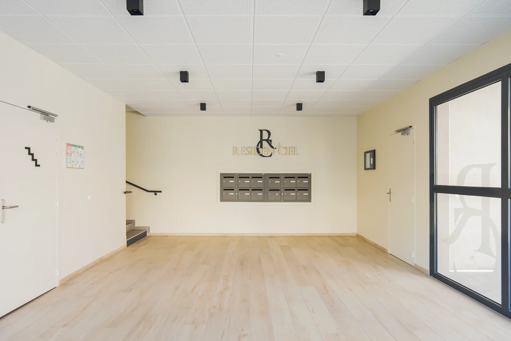 Le hall privilégie une composition sobre et lumineuse, associant teintes claires, sol chaleureux et signalétique discrète.