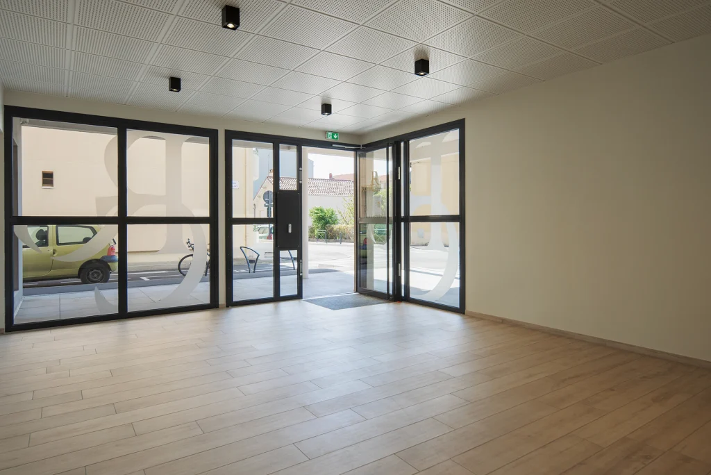 Les larges surfaces vitrées du hall renforcent la lumière naturelle et assurent une relation directe entre les espaces communs et la rue.