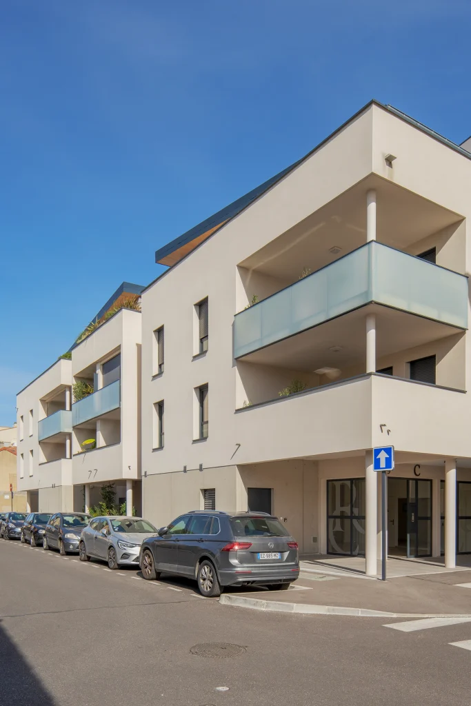 Vue depuis la rue mettant en valeur l’angle du bâtiment et la succession des balcons qui caractérisent l’écriture du projet.
