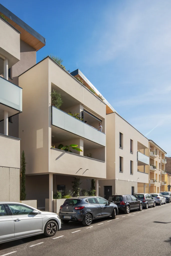 Vue en perspective de la résidence soulignant la succession des balcons, la sobriété des façades et l’intégration dans la rue existante.