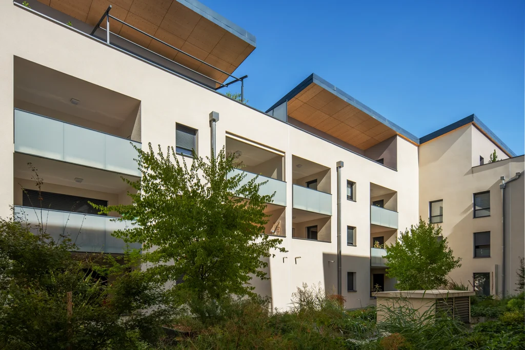 Les niveaux supérieurs s’ouvrent par de grandes terrasses protégées, accompagnées de sous-faces bois qui réchauffent l’écriture architecturale.