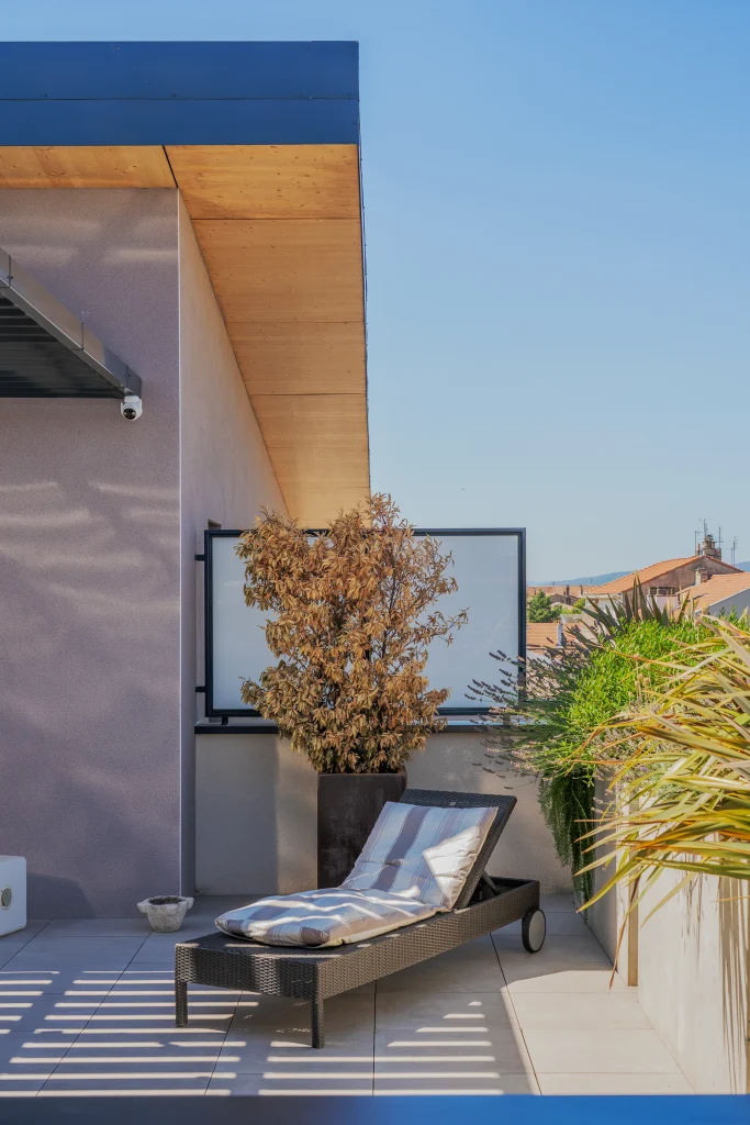 Détail d’une terrasse en attique où la sous-face bois apporte une tonalité chaleureuse à l’architecture contemporaine.