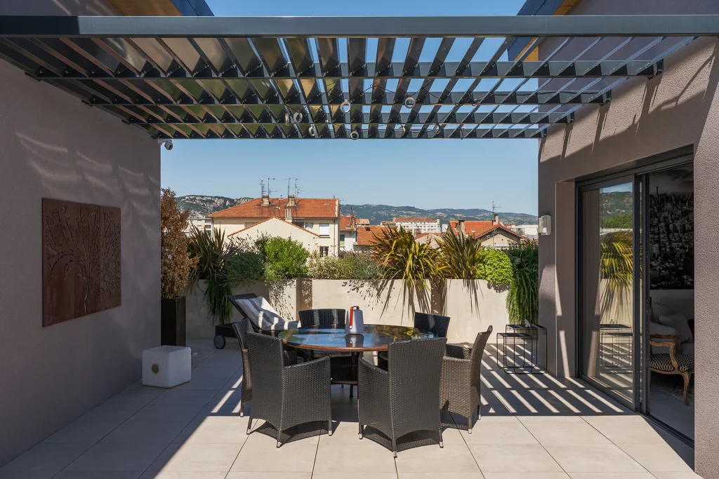 Une vaste terrasse prolonge le logement et bénéficie d’une pergola qui filtre la lumière tout en créant un espace extérieur habitable.