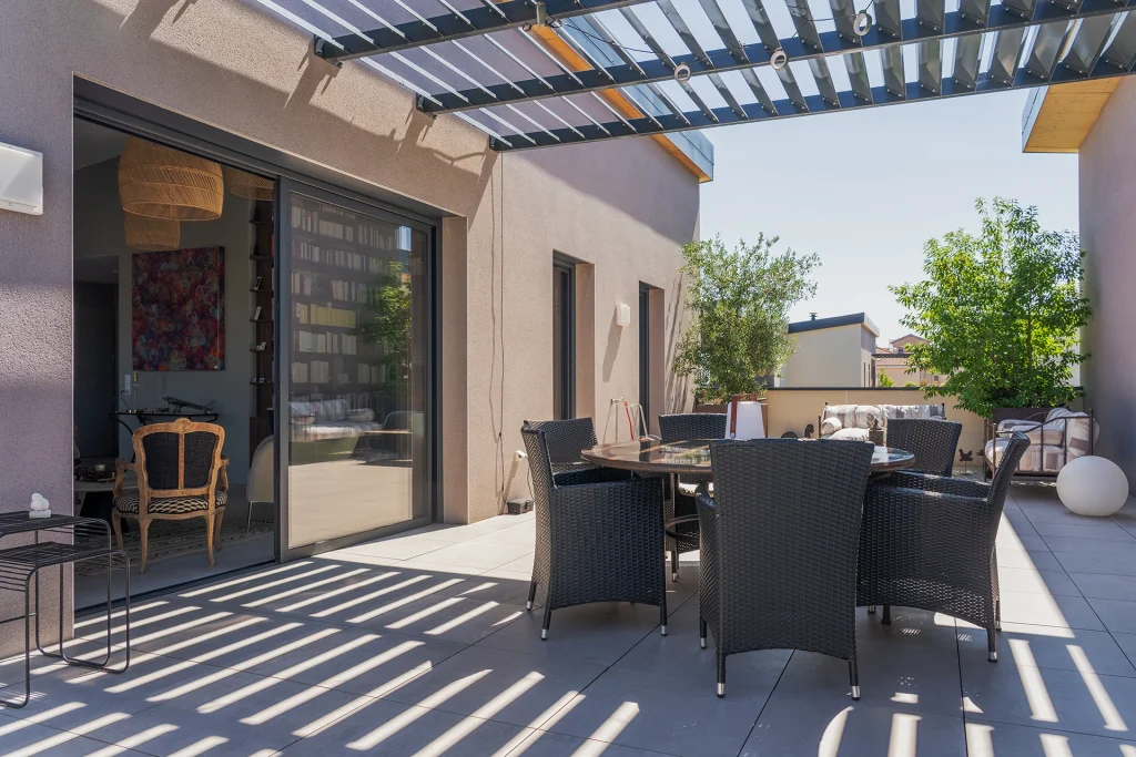 La terrasse constitue une véritable pièce extérieure, protégée par la structure légère de la pergola et directement reliée aux espaces intérieurs.