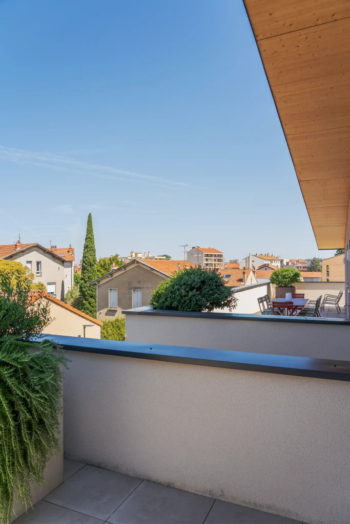 Une terrasse en hauteur offre une ouverture dégagée sur le quartier tout en conservant une relation intime avec le logement.